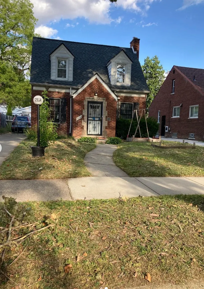 The same brick colonial after service, with a freshly cut lawn and a clean walkway
