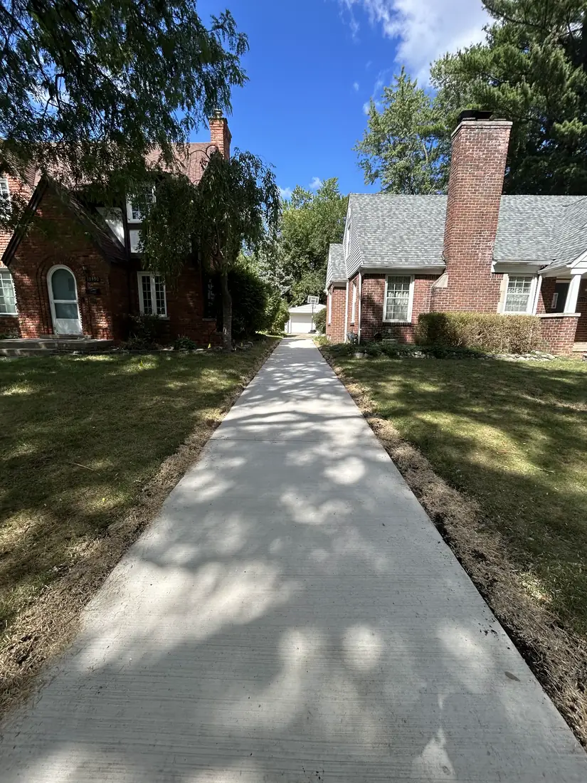 Newly poured concrete walkway between two brick homes