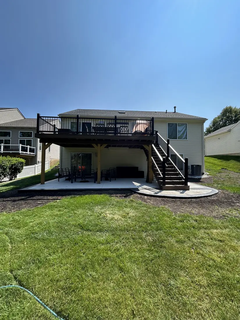 The same home after construction, with a new elevated deck, stairs and a concrete patio