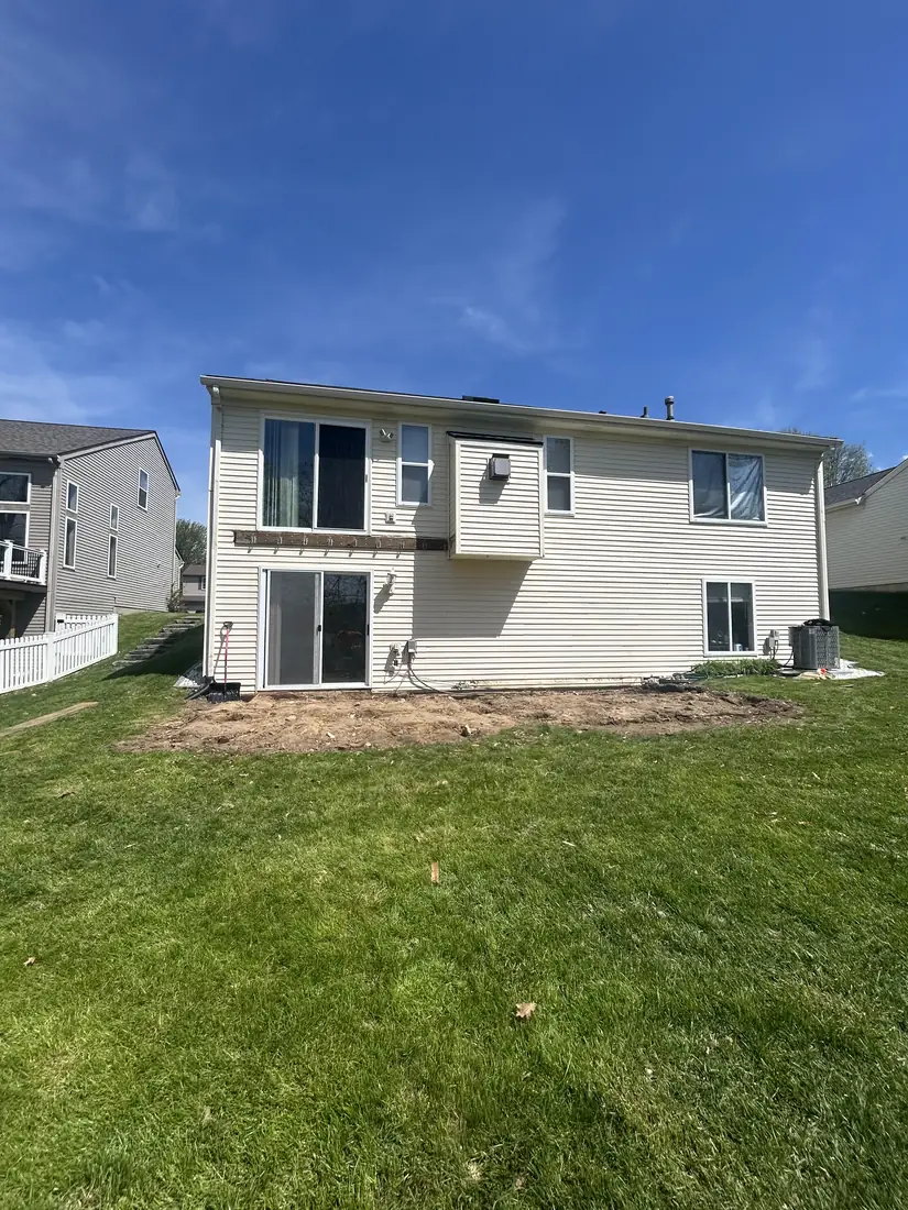 Back of a two-story home before construction, with bare dirt and no deck